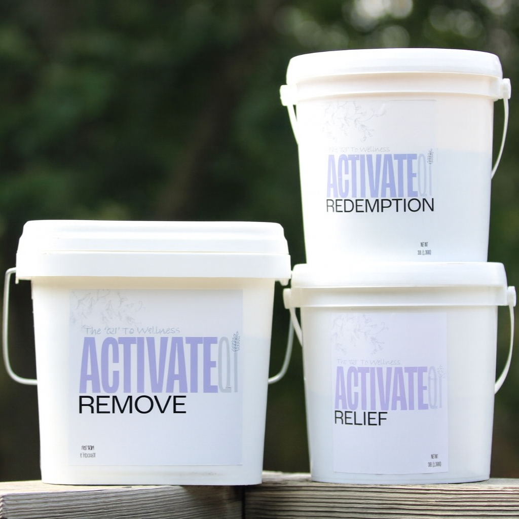 Three white buckets with 'ActivateQi' branding on a wooden surface with a blurred natural background.