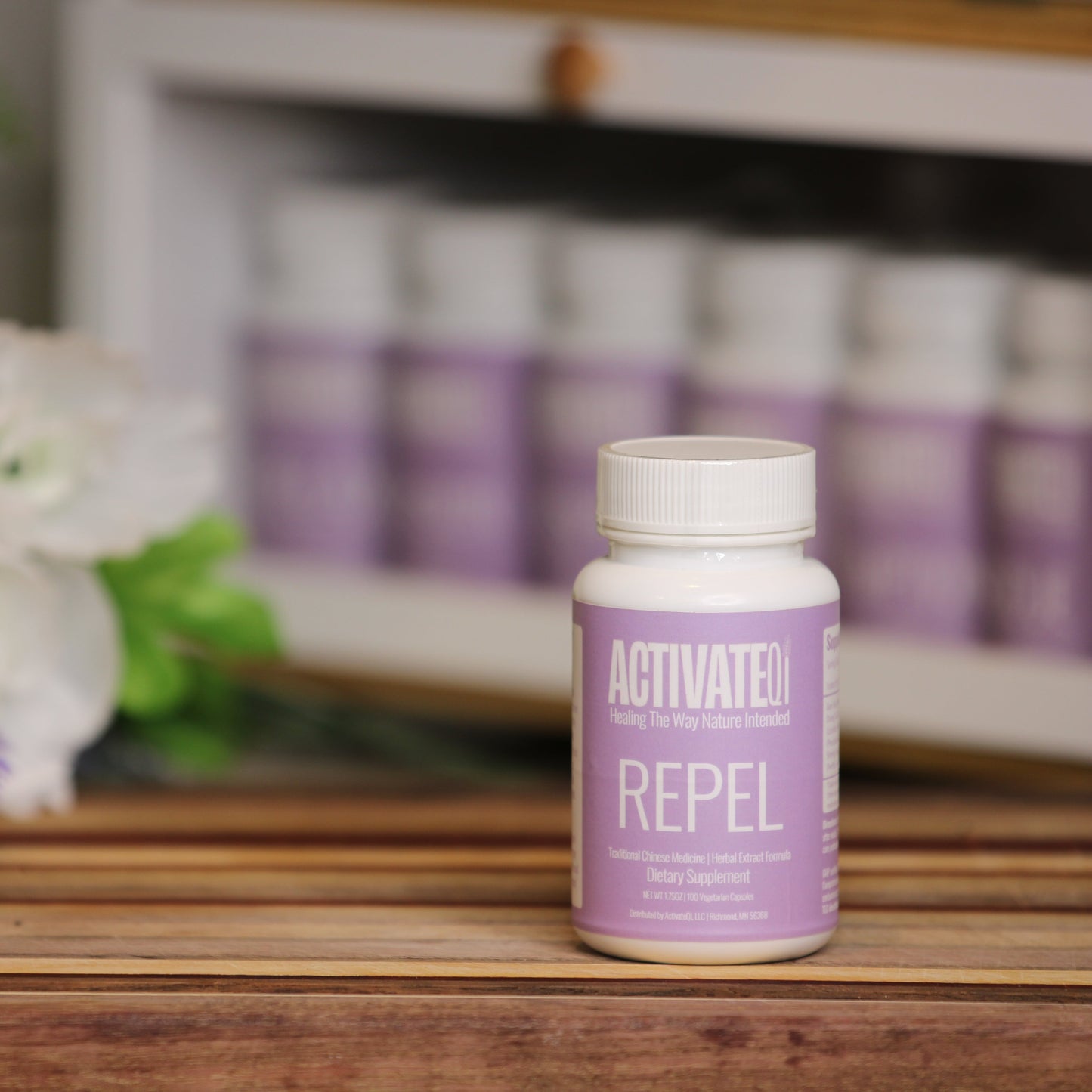 Activate Repel bottle on a wooden surface with flowers and more bottles in the background