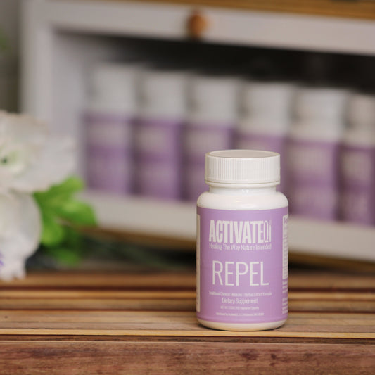 Activate Repel bottle on a wooden surface with flowers and more bottles in the background
