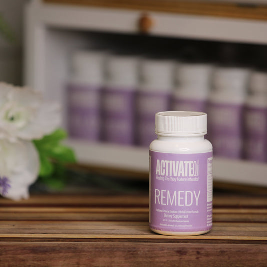 ActivatedQi Remedy bottle on a wooden surface with flowers and more bottles in the background